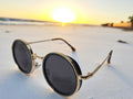 calypso green sunglasses front side angle on a beach