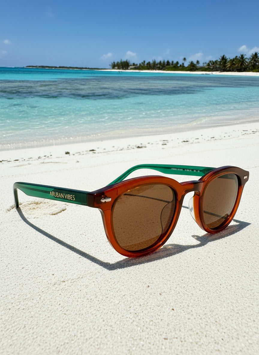 Sunglasses on a sandy beach with ocean and clear sky in the background